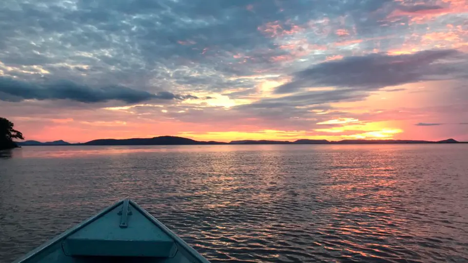 Pôr do sol sobre a água, visto da proa de um barco